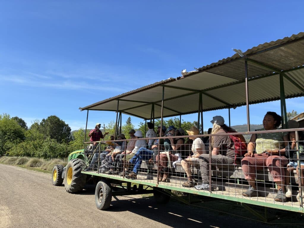 A group of people on a wagon being pulled by a tractor.