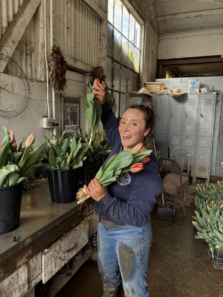 Hannah holding a bunch of tulips in her left hand and adding one more with her right.
