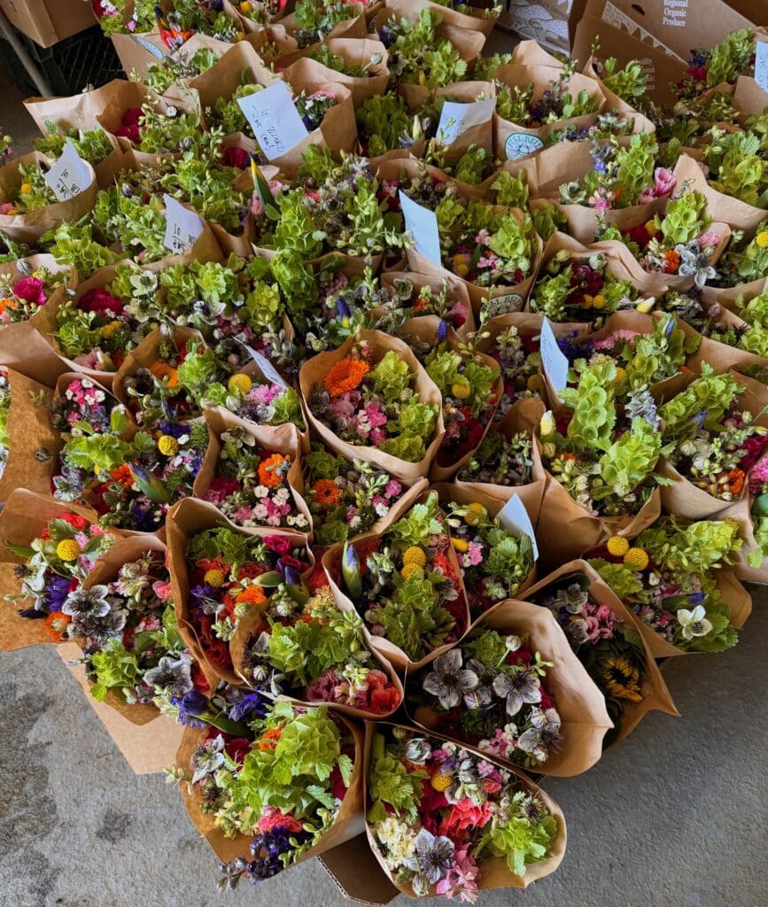Overhead shot of mixed bouquets of flowers in boxes. The bouquets have paper sleeves.